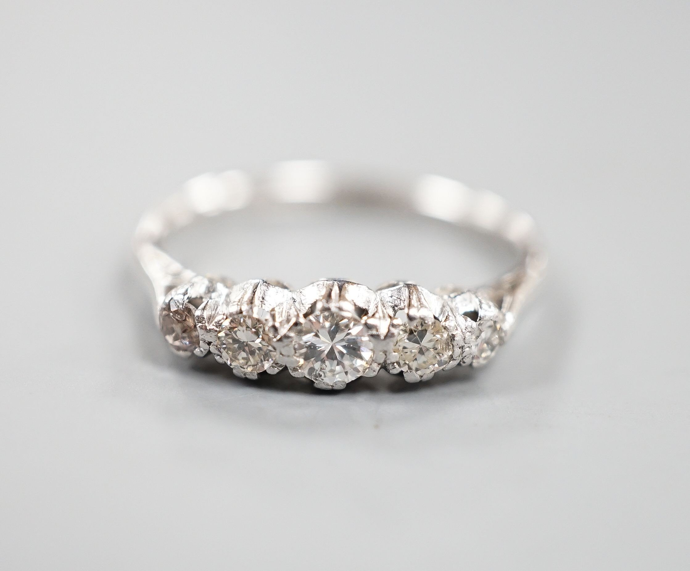 An 18ct & plat, graduated five stone diamond half hoop ring, size L/M, gross weight 2 grams.